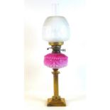 A Victorian paraffin lamp, with pink moulded glass reservoir, brass reeded column, etched clear