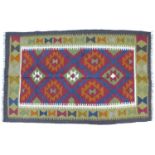 A Maimana Kilim rug with dark blue ground, three white, red, and olive green lozenges, white and