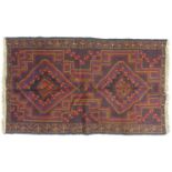 A Baluchi rug with red ground, two medallions in shade varying shades of brown with thin red and