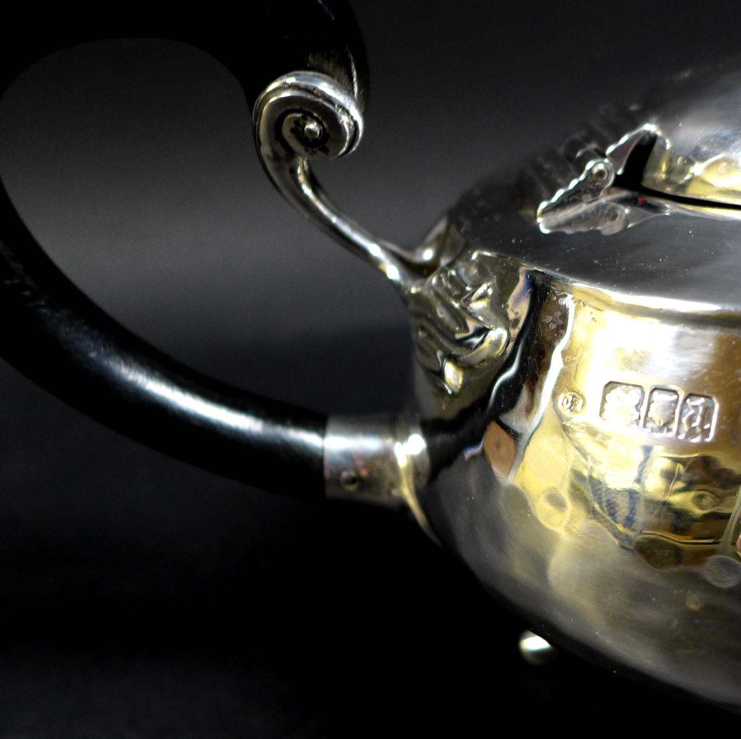 An Arts & Crafts silver teapot, of compressed ovoid form, with all over hammered finish, ebonised - Image 8 of 9