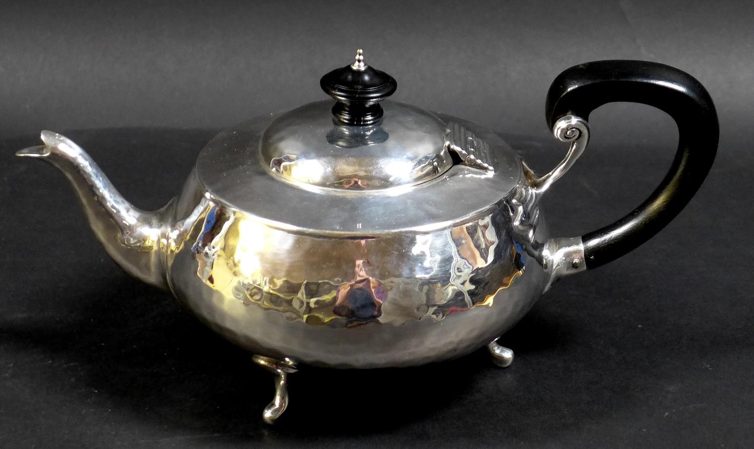 An Arts & Crafts silver teapot, of compressed ovoid form, with all over hammered finish, ebonised