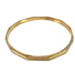 A 9ct gold bangle with faceted sides and Greek key engraved decoration, 10.2g.
