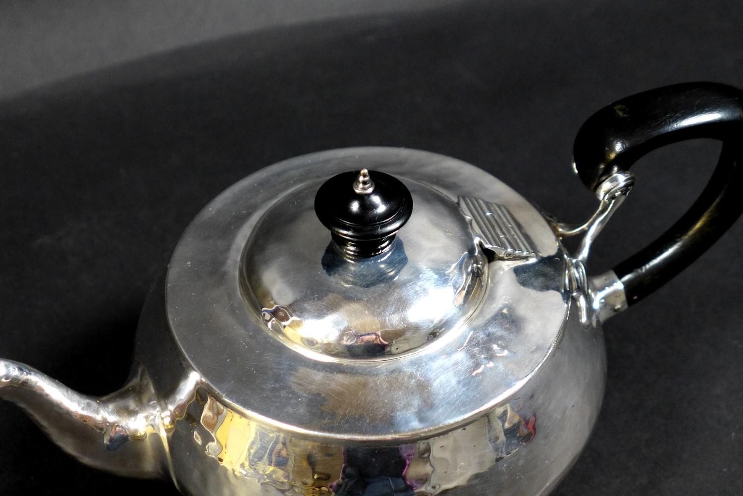 An Arts & Crafts silver teapot, of compressed ovoid form, with all over hammered finish, ebonised - Image 2 of 9