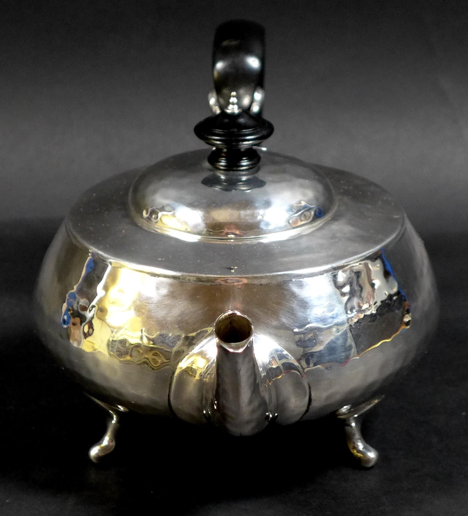 An Arts & Crafts silver teapot, of compressed ovoid form, with all over hammered finish, ebonised - Image 5 of 9