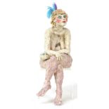 A clay sculpture of a female artiste, bare breasted and with feathers in her hair, modelled to sit