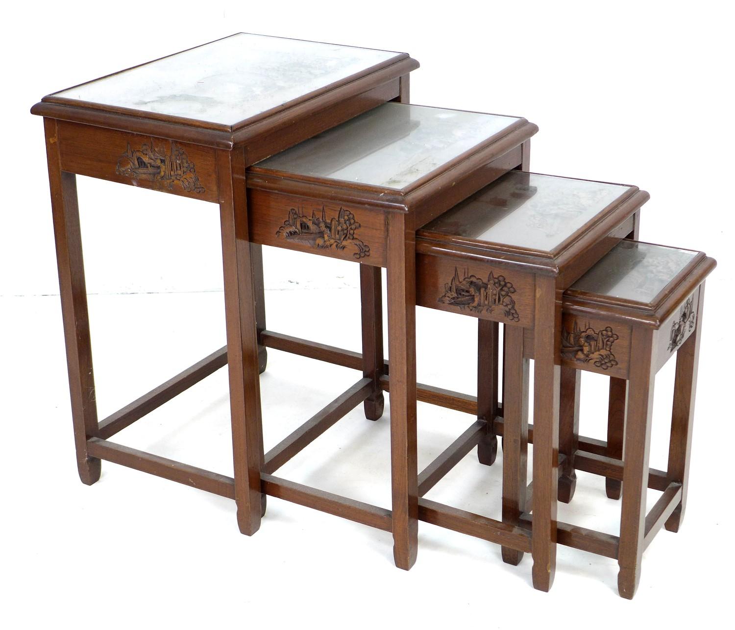 A Chinese hardwood nest of four tables, carved decoration, glass tops, largest 51 by 35 by 64cm