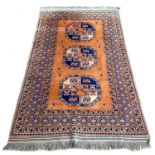 A Tekke rug with orange ground, three large dark blue guls, 225 by 132cm.