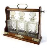 A Victorian oak tantalus, with EPNS mounts and three clear glass hobnail cut decanters, with key, 34