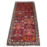 A Hamadan runner rug with red ground, the field decorated with pairs of stylised birds and