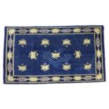 A Chinese rug with dark blue ground, diamond patterned field scattered with eleven cream floral