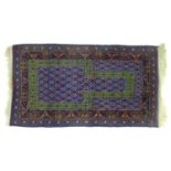A Persian prayer rug with blue ground, green stylised arch on the purple and cream decorated