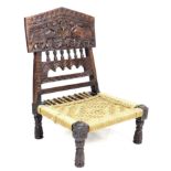 An African carved low seat, mid 20th century, the fold-down back varved with two elephants, woven