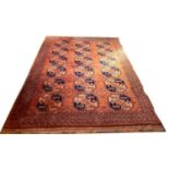 A large Tekke rug with orange ground, three rows of pink and dark blue guls, 360 by 250cm.
