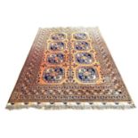 A Tekke rug with orange ground, eight large dark blue guls, 310 by 208cm.