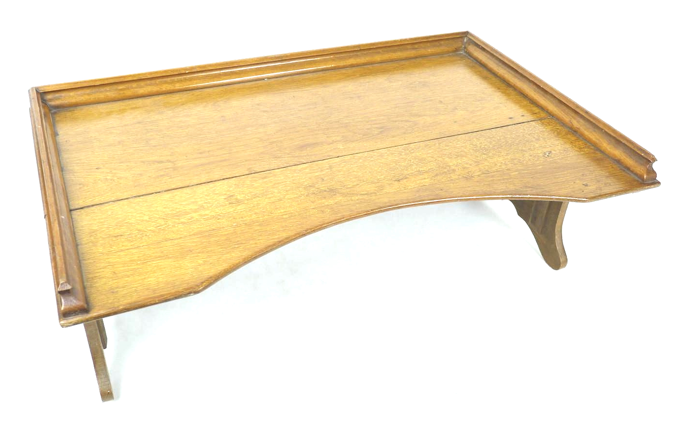 An early to mid 20th century oak bed tray, with folding legs, 68 by 43 by 24cm high, with legs down.