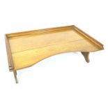 An early to mid 20th century oak bed tray, with folding legs, 68 by 43 by 24cm high, with legs down.