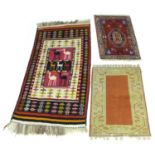 A group of three small rugs, comprising a flat weave rug with seven camels to the red, cream, and