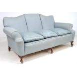 An Edwardian three seater settee, shaped back, loose seat cushions, upholstered in pale blue fabric,