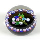 A Paul Ysart style paperweight, the black ground with posy of spring flowers to the centre, bordered