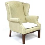 A George III style wing armchair, upholstered in pale green and gold striped fabric, raised on