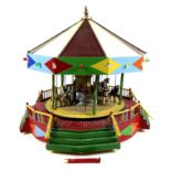 A vintage moving model of a fairground carousel, with detailed modelling and decoration, likely