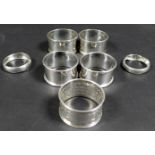 A collection of seven George V silver napkin rings, comprising a pair of napkin rings with reeded