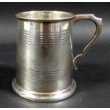 A George V silver 1/2 pint tankard, with stepped rim and base, scroll handle and two bands of reeded