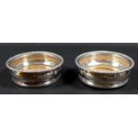 A pair of William IV silver plated wine coasters, with decorative rims and wooden bases inset with a