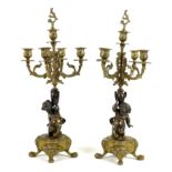 A pair of bronze and gilt metal candelabra, each modelled as a putto holding an urn below a four