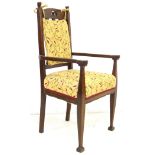 An Arts and Crafts oak open arm chair, with carved back rails, the seat upholstered in yellow, 54 by