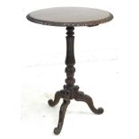 A late Victorian oak wine table, the circular surface with carved gadrooned edge, raised on a lappet