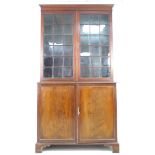 An Edwardian mahogany bookcase, with astragal glazed double doors, above a cupboard base, raised