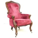 A Victorian spoon back nursing chair, with carved top rail, raised on cabriole legs with castors,