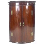 A George III mahogany bow fronted corner cupboard, with green painted interior, 72 by 50 by 106cm