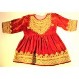 Koochi nomad, Afghanistan. A baby dress in velvet with couched golds thread decorations. The