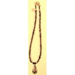White metal pendant on necklace of garnet beads. 30cm.