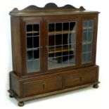 An Edwardian oak bookcase, circa 1900, the upper section with three leaded panel glazed doors,