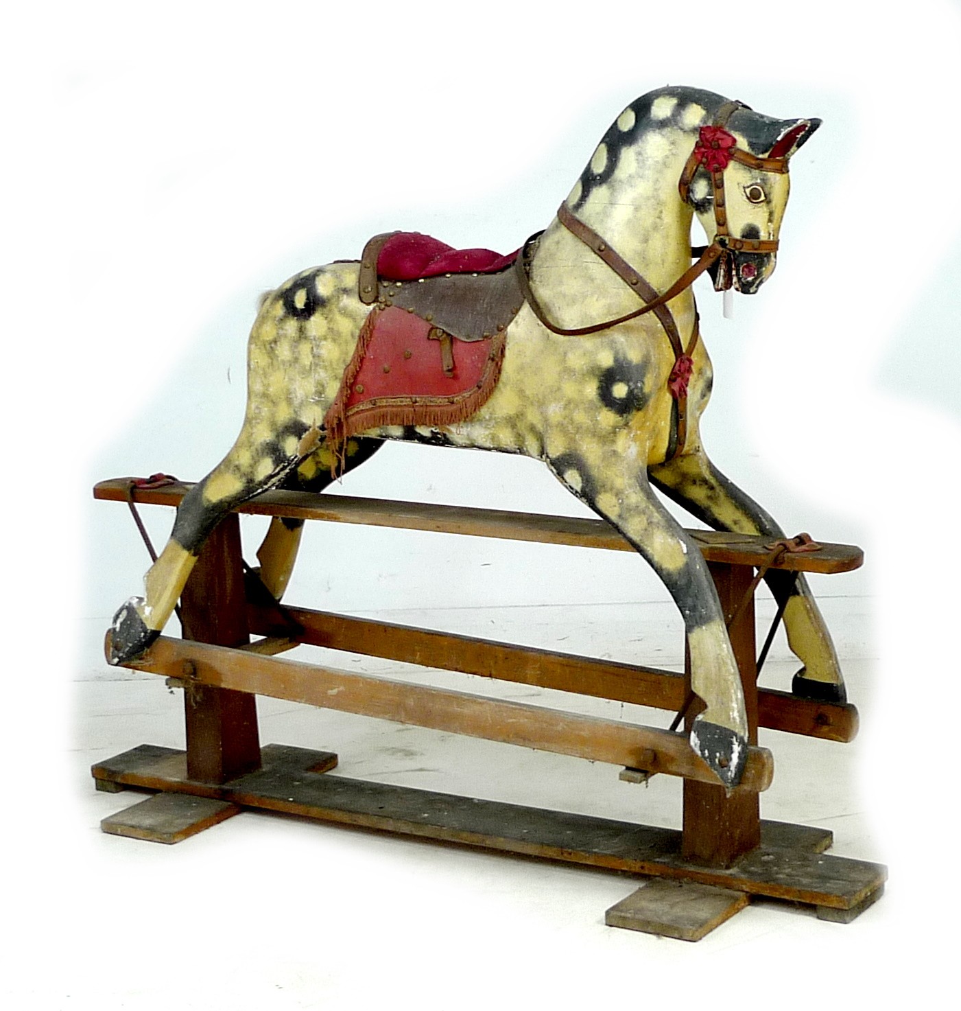 A mid 20th century carved wooden rocking horse, dappled grey coat, red saddle, on a pine base with