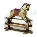 A mid 20th century carved wooden rocking horse, dappled grey coat, red saddle, on a pine base with