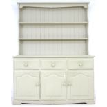 A modern pine pale green painted dresser, with plate rack over three drawers and three cupboards