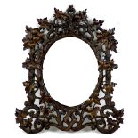 A late 19th century Black Forest carved wall mirror, with oval plate, the framed carved as scrolling