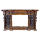 A carved oak overmantel mirror, the bevelled rectangular plate flanked by carved panels and four