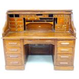 An Edwardian oak roll top desk, fitted with an arrangement of small drawers and pigeon holes