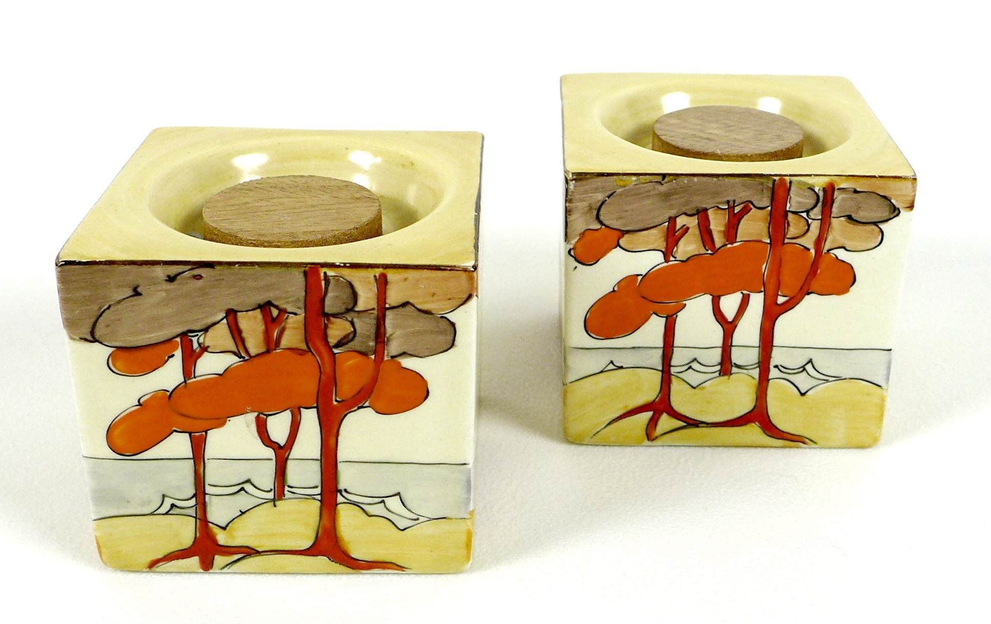 A pair of Clarice Cliff bizarre cuboid candlesticks, hand painted in the Coral Firs pattern, shape