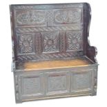 A late Victorian oak settle, carved decoration, lift lid to the box seat, 125.5 by 51 by 137cm high.