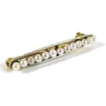 An Edwardian 15ct gold and platinum bar brooch set with thirteen seed pearls, 2.9cm, 1.9g.