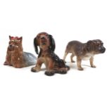 A group of three dog figurines, comprising a Beswick 'Yorkshire Terrier - Lying', model 1944, grey