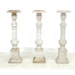 A group of three cast iron white painted column pricket candlesticks, each with baluster columns, on