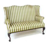 A Victorian wing settee, two seater, high back, upholstered in striped dark green and gold floral