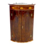 A George III mahogany bow fronted corner cupboard, with shell inlaid frieze below a cavetto cornice,